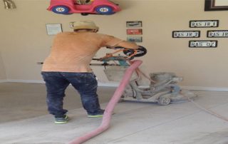This image shows a man grinding the floor in preparation for epoxy painting.