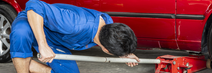 This image shows a man placing a jack under a car.