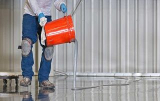 This image shows a man pouring epoxy paint on the floor.